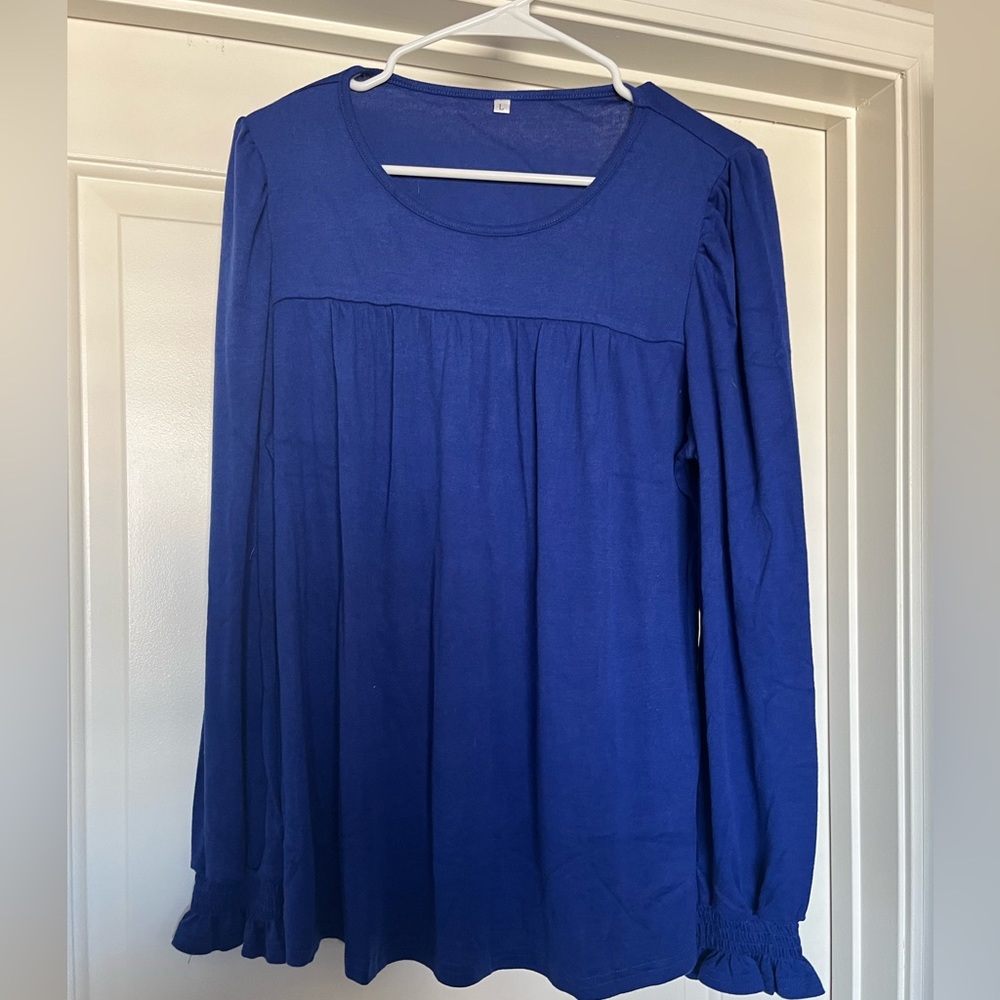 Blue long sleeved shirt with ruffled sleeves. Size Large. Never worn, gifted.
